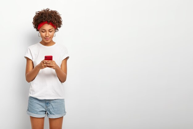 Filmación en interiores de mujer atractiva mira la pantalla del teléfono inteligente.