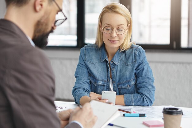 Filmación en interiores de mujer rubia tener conversación de negocios con un colega