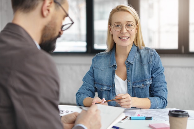 Filmación en interiores de mujer rubia tener conversación de negocios con un colega