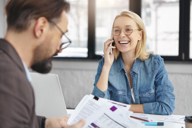 Filmación en interiores de mujer rubia tener conversación de negocios con un colega