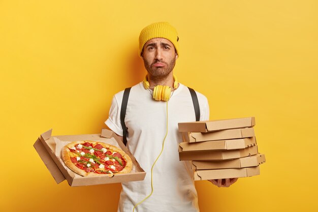 Filmación en interiores de repartidor triste con cajas de pizza