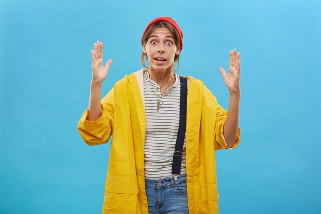 Filmación en interiores de trabajadora sorprendida que muestra el tamaño. Hermosa mujer que demuestra el tamaño de algo grande o enorme con las manos. Mujer asombrada gesticulando sobre pared azul