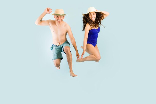Por fin estamos de vacaciones. Novio y novia emocionados saltando en el aire y divirtiéndose en la playa o en la piscina durante el verano
