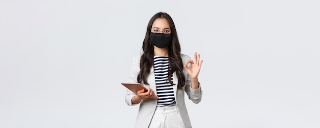 Finanzas comerciales y empleo covid19 prevención de virus y concepto de distanciamiento social Empresaria asiática con tableta digital usa máscara protectora contra virus y muestra un signo de aprobación