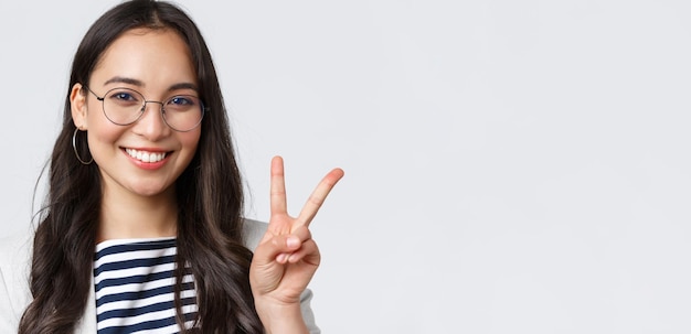 Finanzas empresariales y empleo concepto de emprendedoras exitosas femeninas Primer plano de un empleado de oficina asiático saliente amistoso que muestra el signo de la paz y sonríe optimista tiene todo bajo control