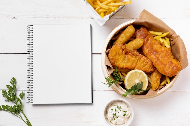 Foto gratuita fish and chips en un tazón con limón y cuaderno