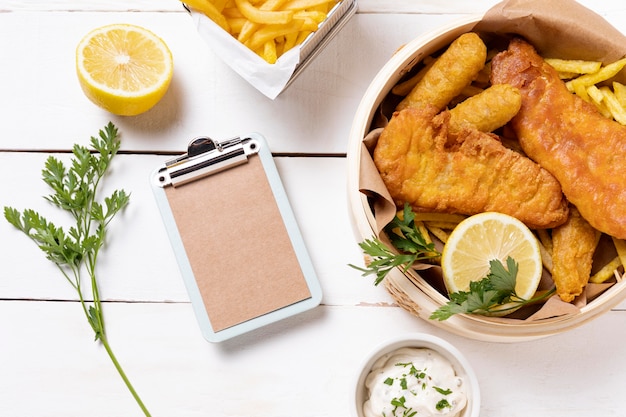 Fish and chips en un tazón con limón y portapapeles