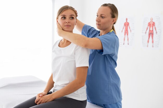 Fisioterapeuta ayudando a una paciente joven en su clínica