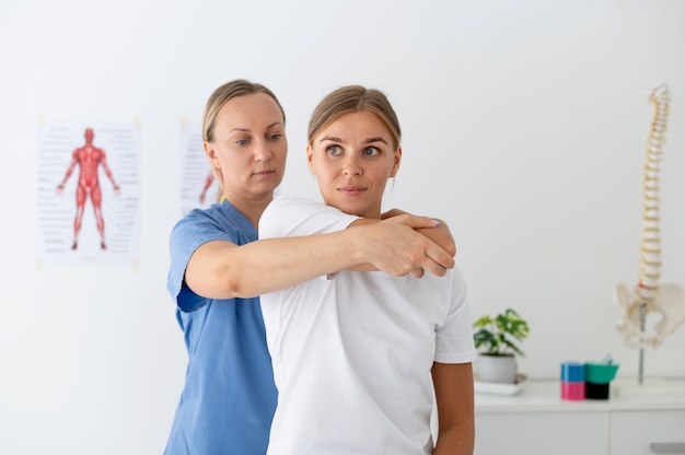 Foto gratuita fisioterapeuta ayudando a una paciente en su clínica