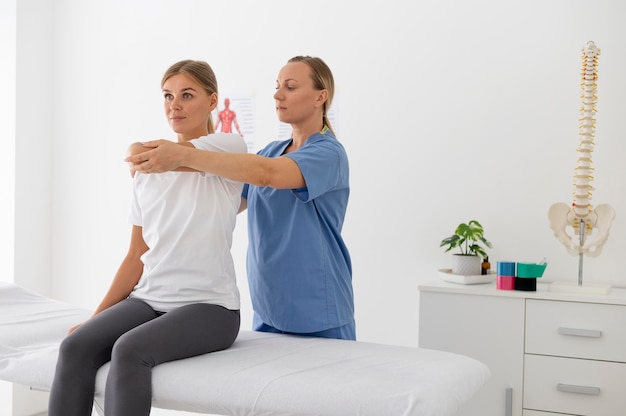 Foto gratuita fisioterapeuta ayudando a una paciente en su clínica