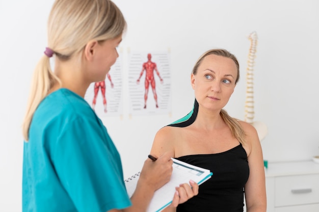 Foto gratuita fisioterapeuta ayudando a un paciente en su clínica