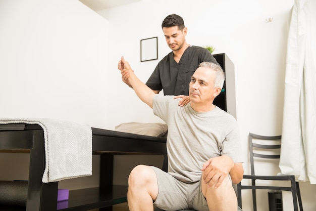 Foto gratuita fisioterapeuta ayudando a pacientes mayores con ejercicio manual en clínica de fisioterapia