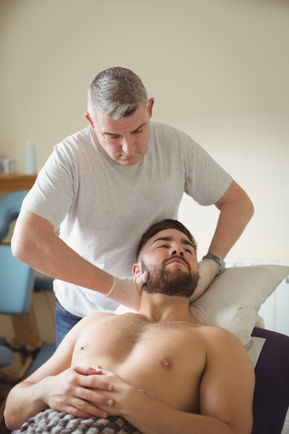 Fisioterapeuta examinando el cuello de un paciente