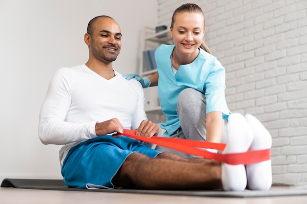 Fisioterapeuta hombre y mujer haciendo ejercicios con banda elástica