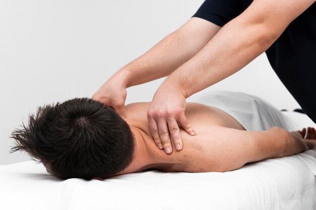 Fisioterapeuta masajeando la espalda del hombre.