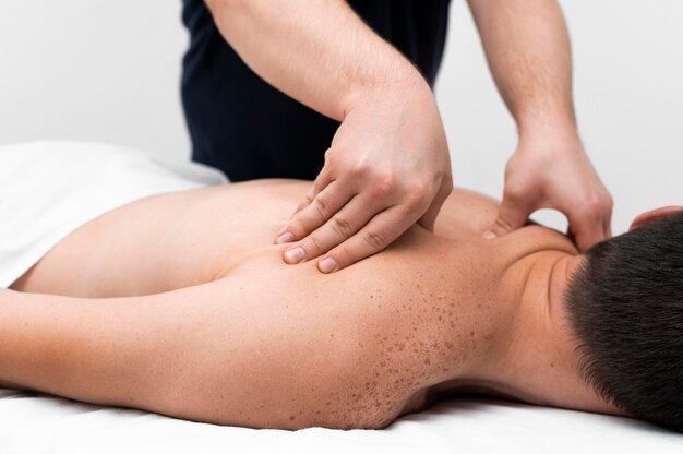 Fisioterapeuta masajeando la espalda de un paciente masculino