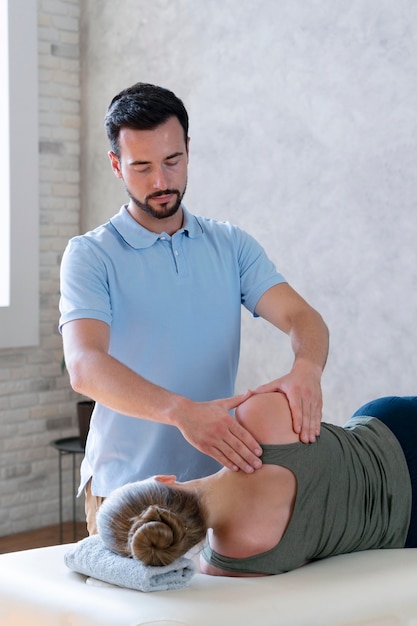 Foto gratuita fisioterapeuta masajeando plano medio del paciente