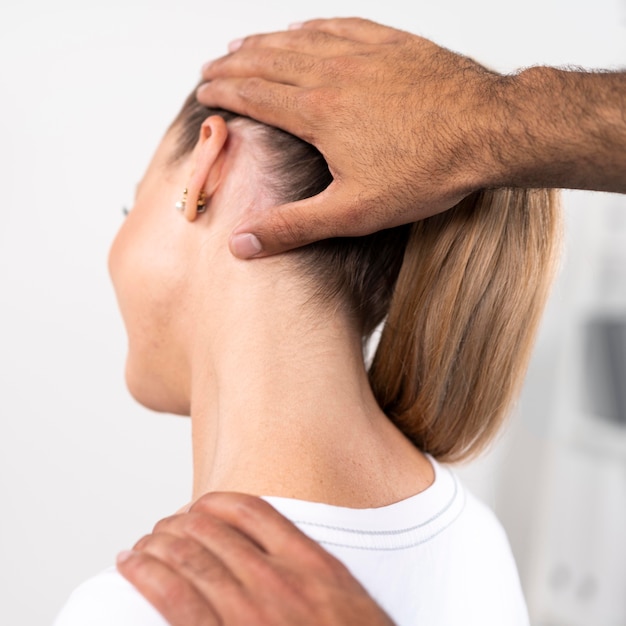 Foto gratuita fisioterapeuta masculino comprobando el cuello de la mujer