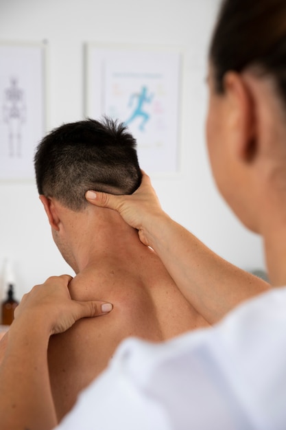 Fisioterapeuta realizando masaje terapéutico en cliente masculino