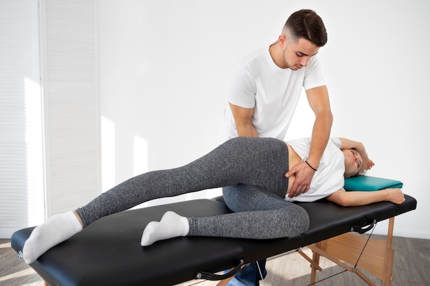 Fisioterapeuta de tiro completo ayudando a mujer