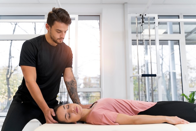 Foto gratuita fisioterapeuta de tiro medio ayudando al paciente