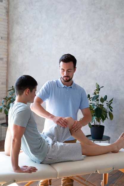 Fisioterapeuta de tiro medio comprobando la pierna