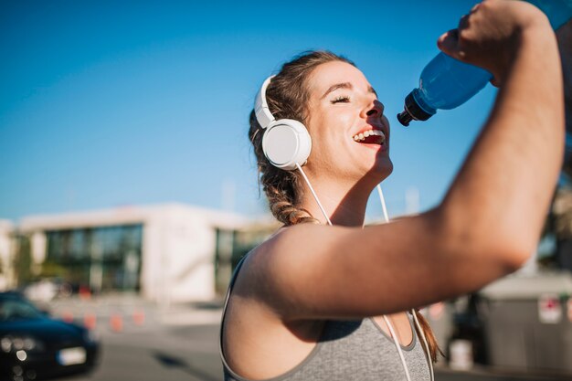 Fit mujer en auriculares con bebida