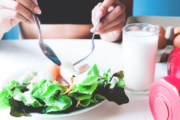 Fitness femenino comer ensalada fresca y leche