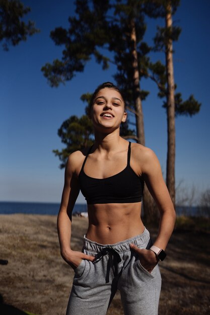 Fitness joven camina en el parque y posando para la cámara