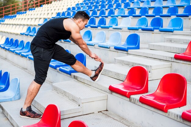 Fitness joven estirando su pierna en gradas