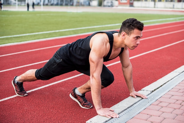 Foto gratuita fitness joven haciendo flexiones en la pista de carreras