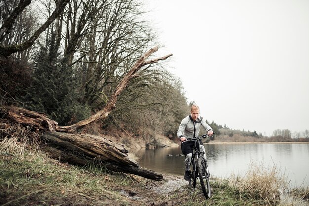 Fitness joven montando bicicleta cerca del lago