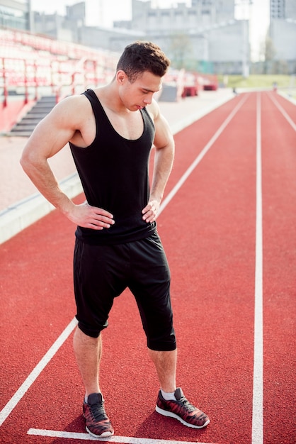 Fitness joven parado en el campo de la pista