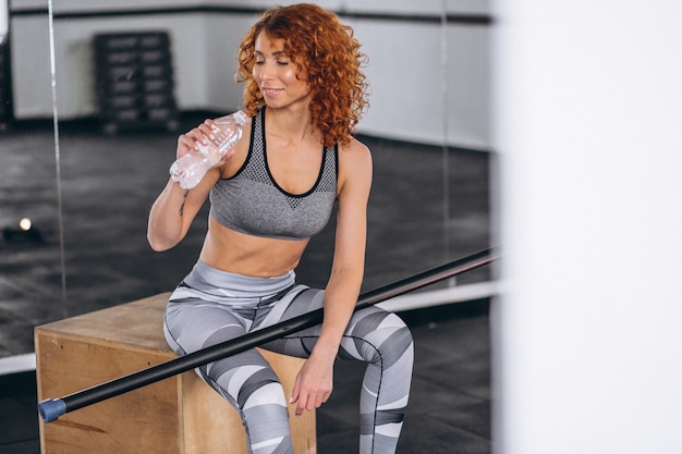 Fitness mujer bebiendo agua de botella en el gimnasio