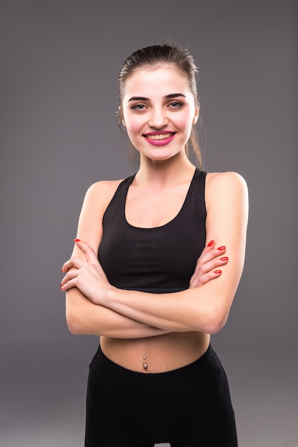 Fitness mujer mujer con cuerpo musculoso listo para entrenar en la pared gris