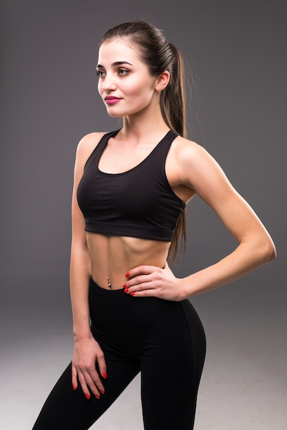 Fitness mujer mujer con cuerpo musculoso listo para entrenar en la pared gris