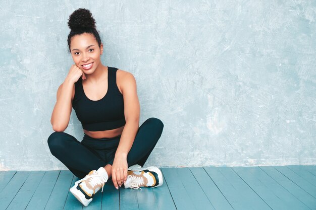 Fitness mujer sonriente en ropa deportiva con peinado de rizos afro