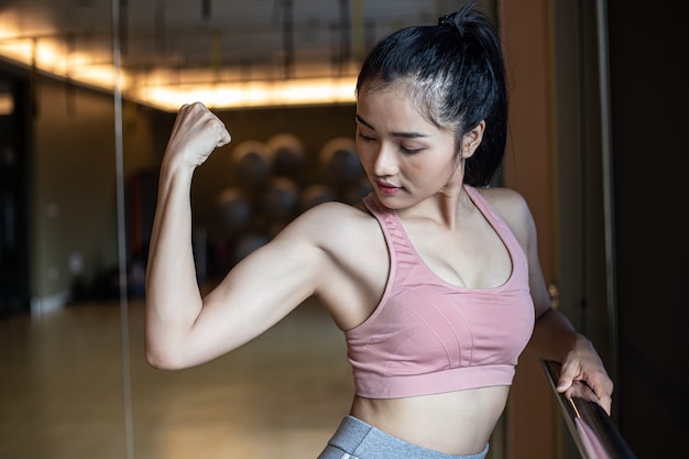 Fitness mujeres muestran los músculos del brazo en el gimnasio.