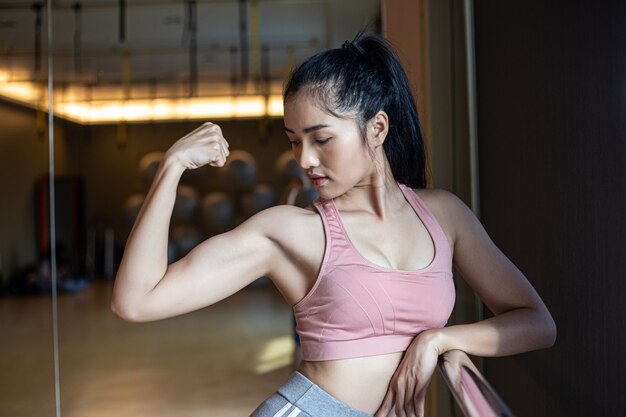 Fitness mujeres muestran los músculos del brazo en el gimnasio.