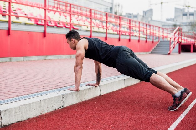 Fitness saludable joven en pista haciendo flexiones