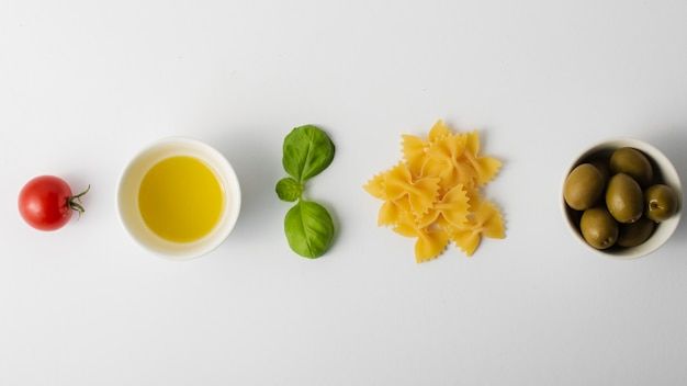 Flat lay sin cocer farfalle tomate y aceitunas