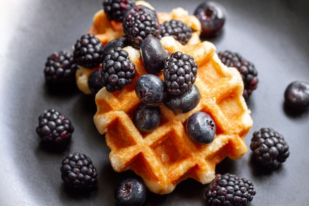 Flat pone frutas del bosque negro en waffles