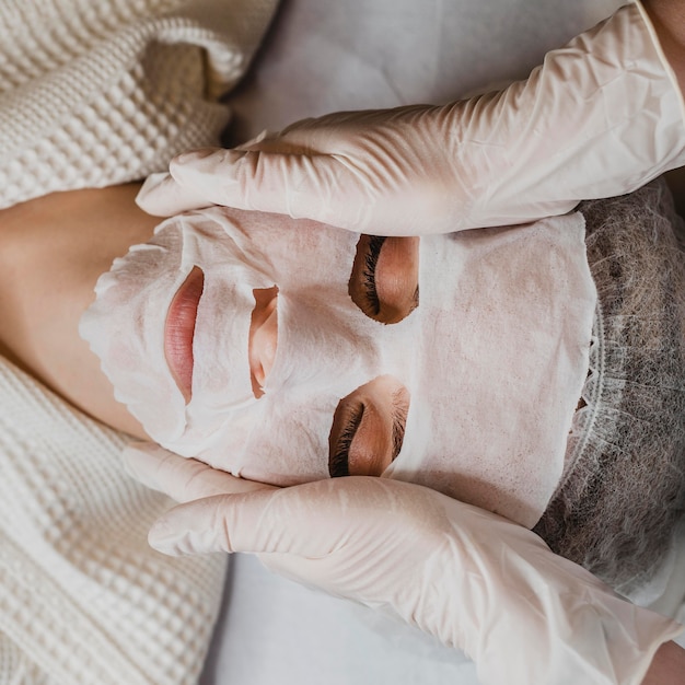 Flay lay de mujer joven recibiendo un tratamiento con mascarilla para la piel