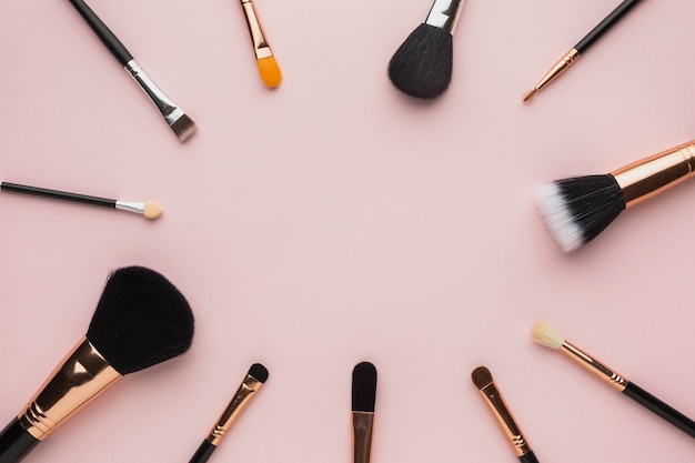 Flay pone marco circular con pinceles de maquillaje y fondo rosa