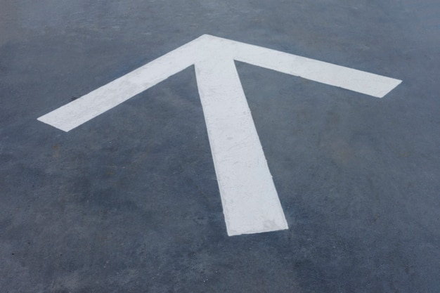 Flecha blanca puntiaguda sobre fondo de asfalto