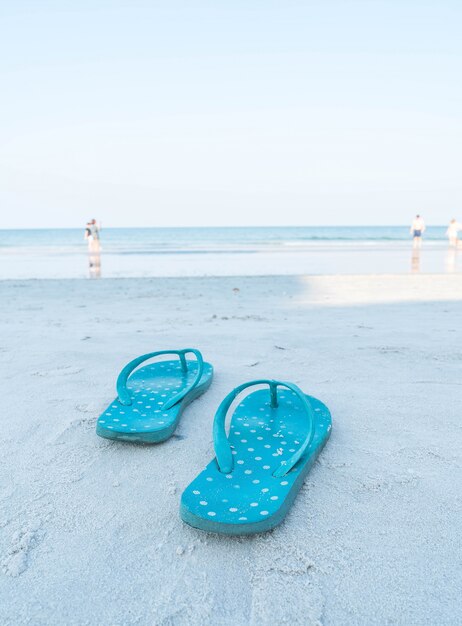 Flipflops en una playa de arena del océano