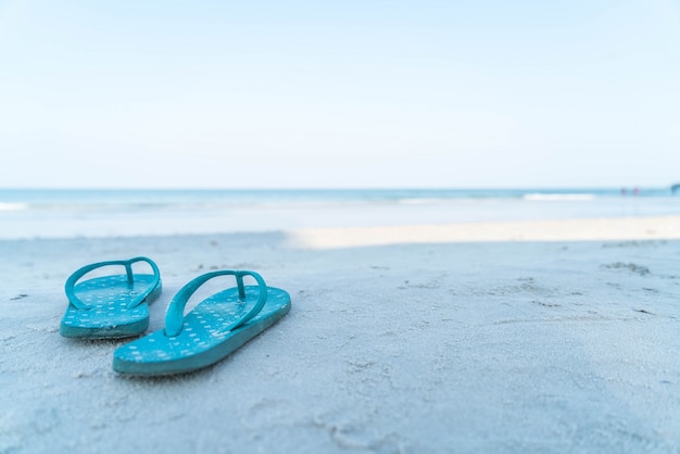 Foto gratuita flipflops en una playa de arena del océano