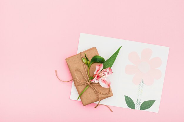 Flor rosa con caja de regalo en mesa rosa