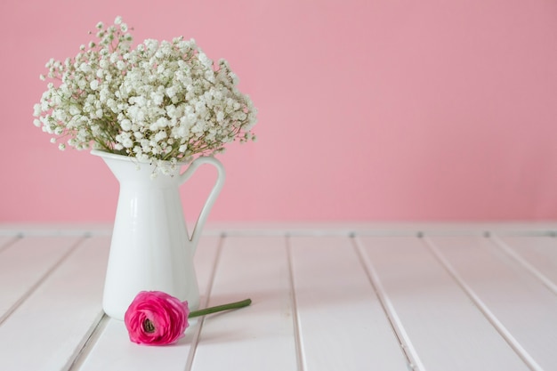 Flor rosa junto a un jarrón decorativo