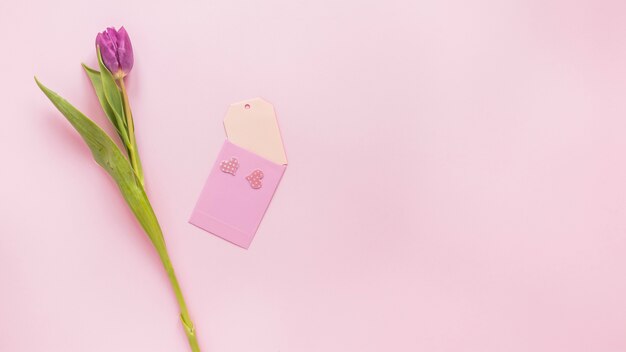 Flor de tulipán morado con papel pequeño en mesa